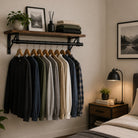 Clothes rail and shelf in a bedroom holding hanging shirts below folded sweaters
