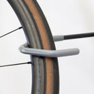 Close-up of a WheelRest hook's grey protective coating cradling a road bike's carbon rim and tan-wall tire to prevent scratches